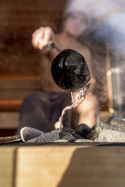 Close-up of steamy sauna stones with ladle